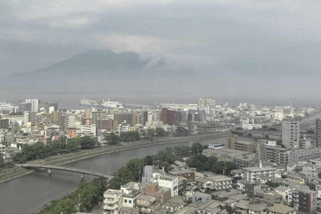シェラトン鹿児島の客室から見た桜島と鹿児島市街。手前に甲突川、港にフェリー。曇りで山頂は雲に隠れている