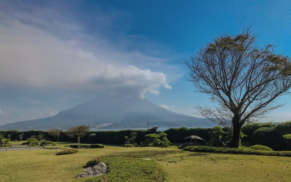 仙巌園の芝生の庭の先に、噴煙を上げる桜島と錦江湾が広がる
