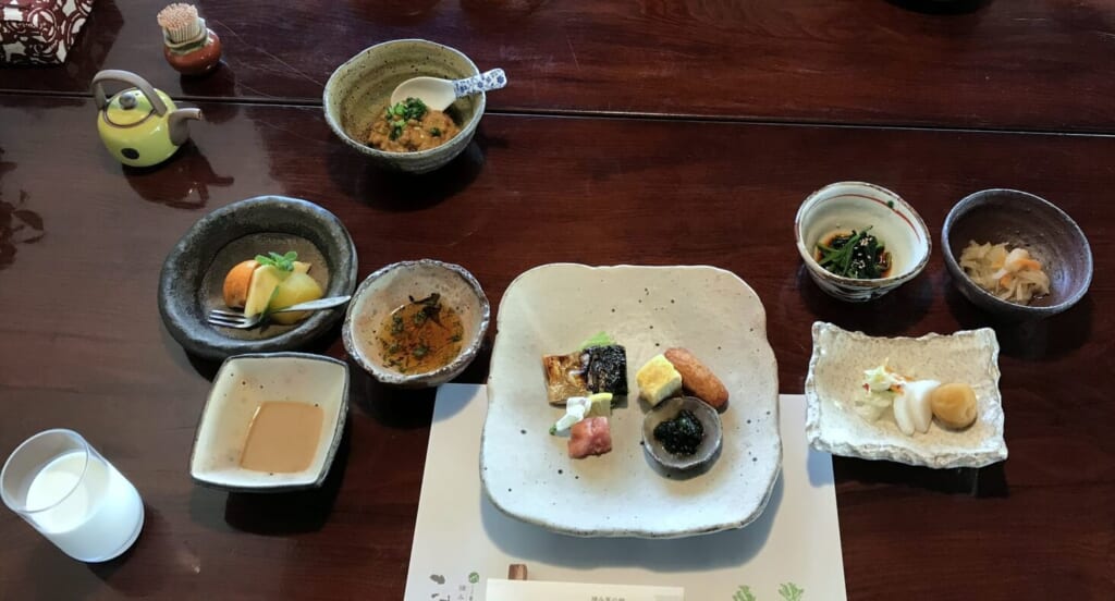 摘み草の宿こまつの朝食。焼き魚や卵焼き、小鉢が並ぶ和の朝食に牛乳が添えられている