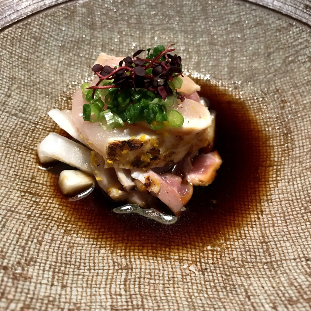 摘み草の宿こまつの夕食の地鶏のタタキ。表面をあぶった地鶏に刻みねぎと芽ものをのせ、たれを張っている
