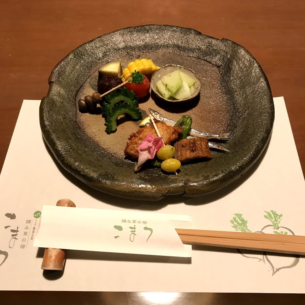 摘み草の宿こまつの夕食の前菜。焼き物の大皿に、季節の野菜や揚げ物、小魚の焼き物を少しずつ盛り合わせている