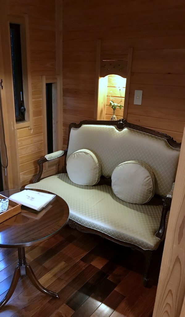 摘み草の宿こまつの客室。板張りの小部屋にソファと丸テーブルがある