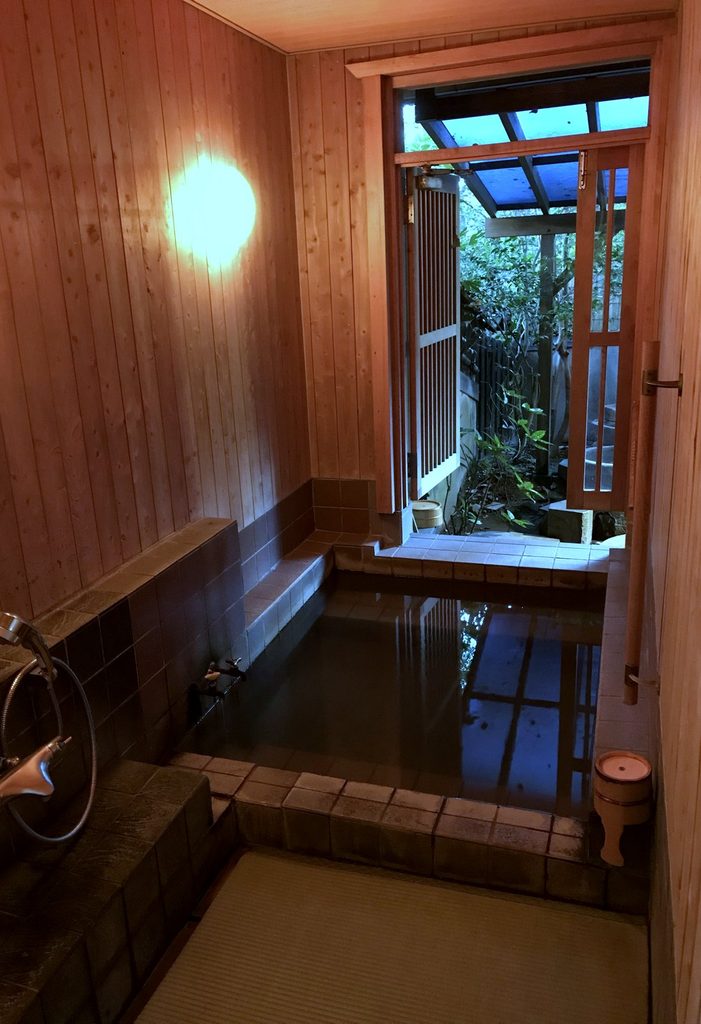 摘み草の宿こまつの内湯。木の壁にタイルの湯船で、床は畳